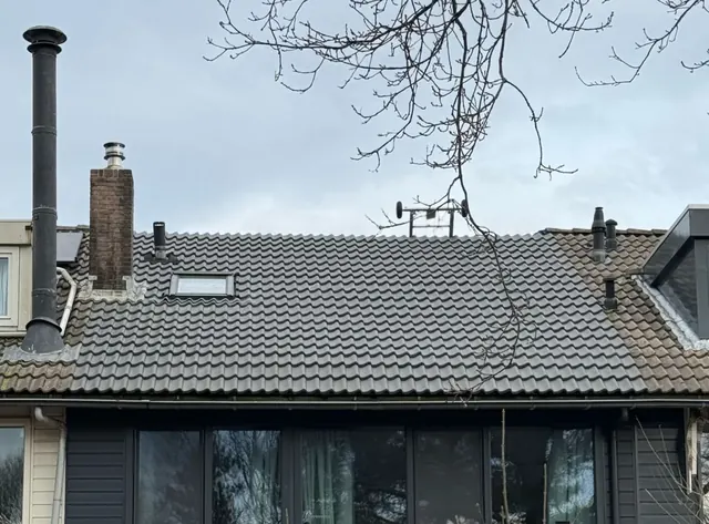 Doorlopend grijs pannendak — Overzicht van een pannendak met nok, schoorsteen en dakdoorvoer.